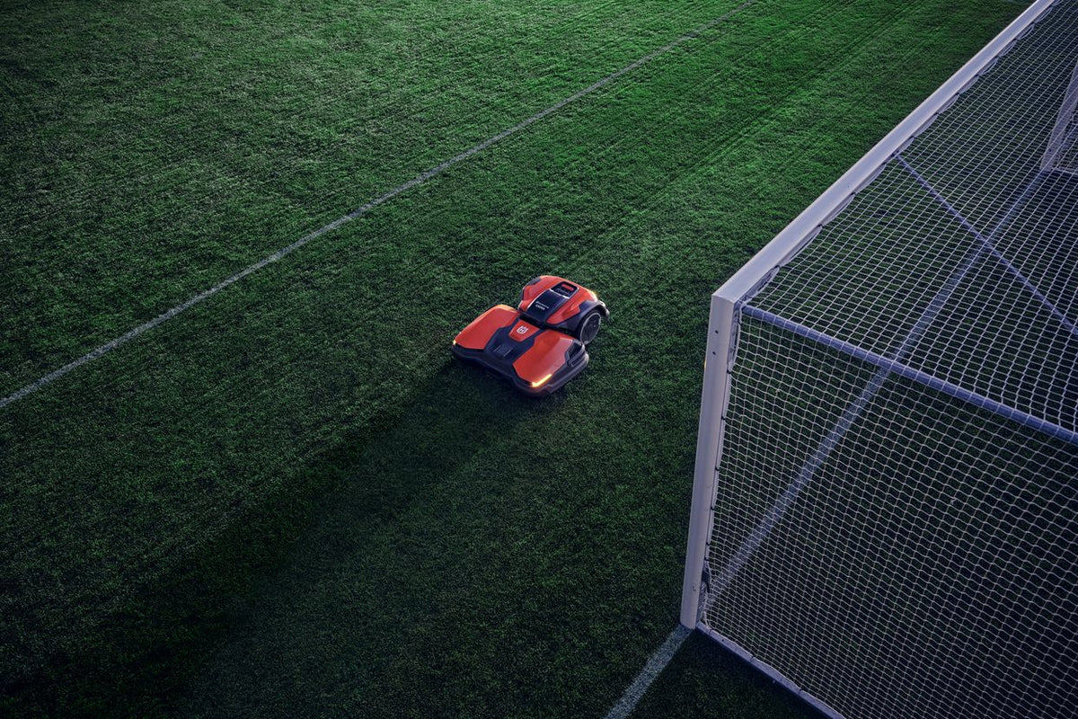 Husqvarna CEORA vicino a una porta da calcio, con il taglio a righe del campo